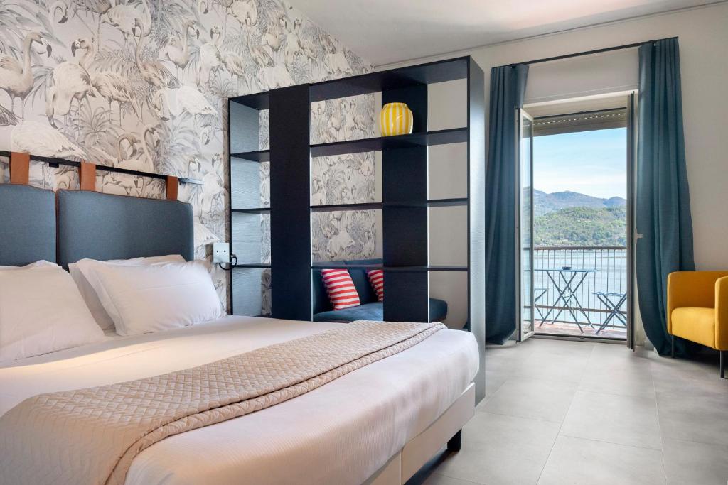 une chambre avec un grand lit et un balcon dans l'établissement Hotel Carillon, à Baveno