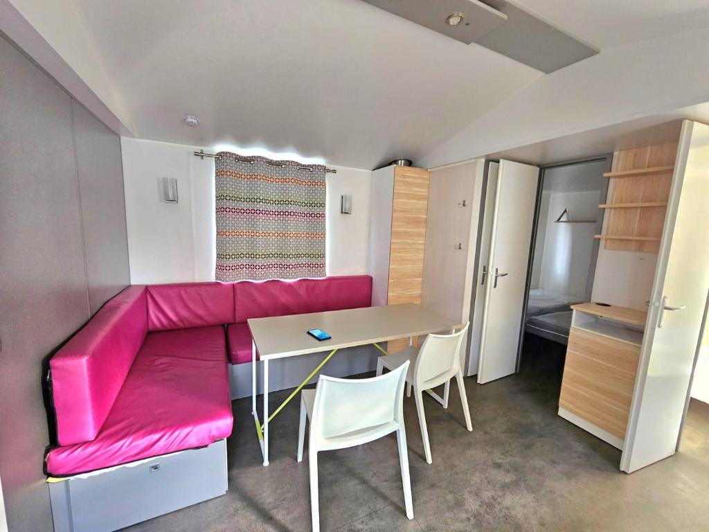 un salon avec un canapé rose et une table dans l'établissement mobil home, à Villeneuve-lès-Maguelone