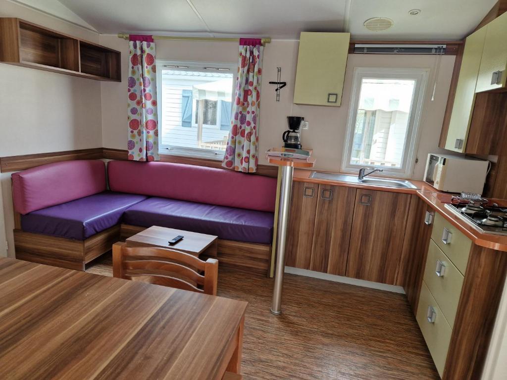 un salon avec un canapé violet dans une cuisine dans l'établissement Camping maeva Escapades Le Bois Joli, à Bois-de-Cené