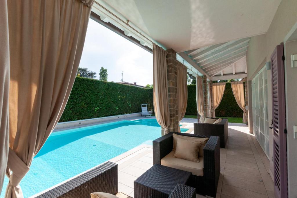 - une piscine avec 2 chaises et un canapé à côté dans l'établissement Villa Giuly, à Sirmione