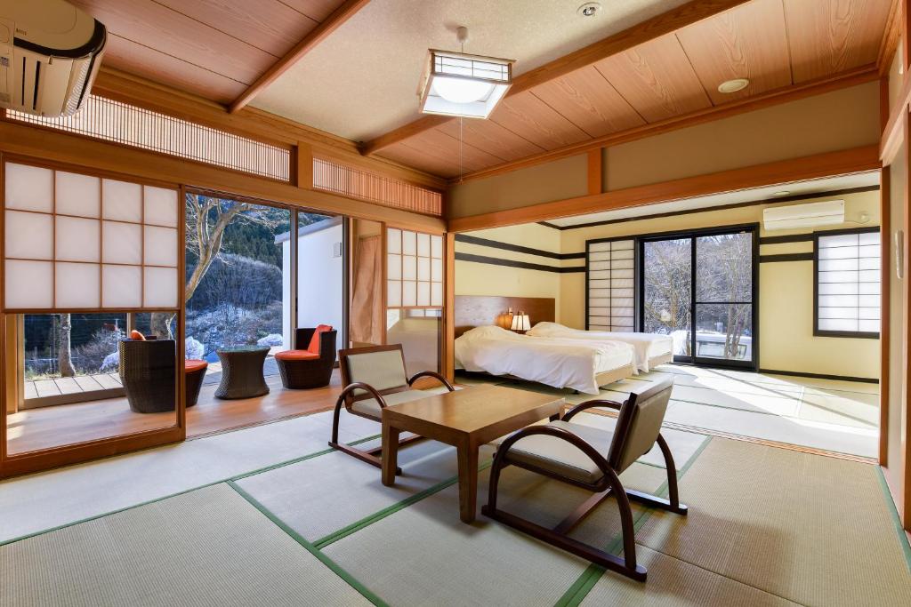 une chambre avec un lit, une table et des chaises dans l'établissement Kinshuusanso, à Kawaba