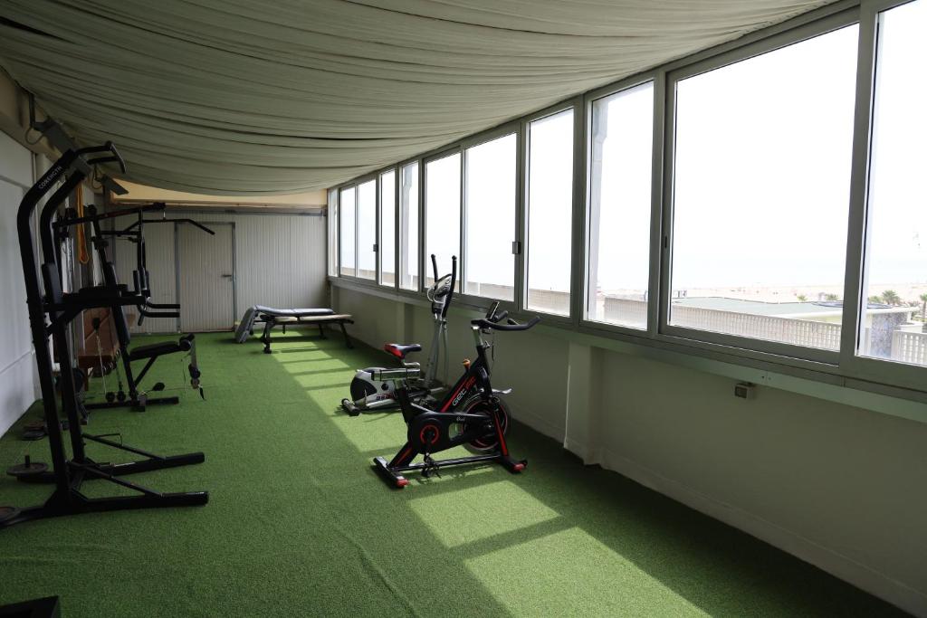 - une salle de sport avec des vélos d'exercice dans une pièce dotée de fenêtres dans l'établissement Hotel Derby, à Rimini