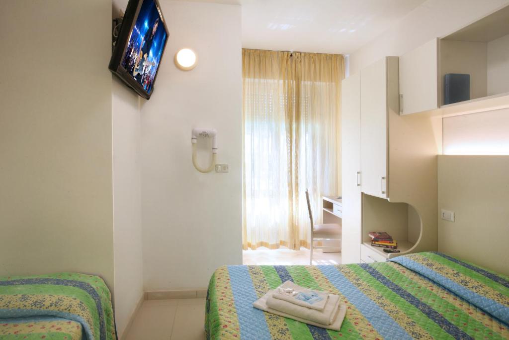 une chambre avec deux lits et une télévision au mur dans l'établissement Hotel Leoni, à Rimini 43 autres photos