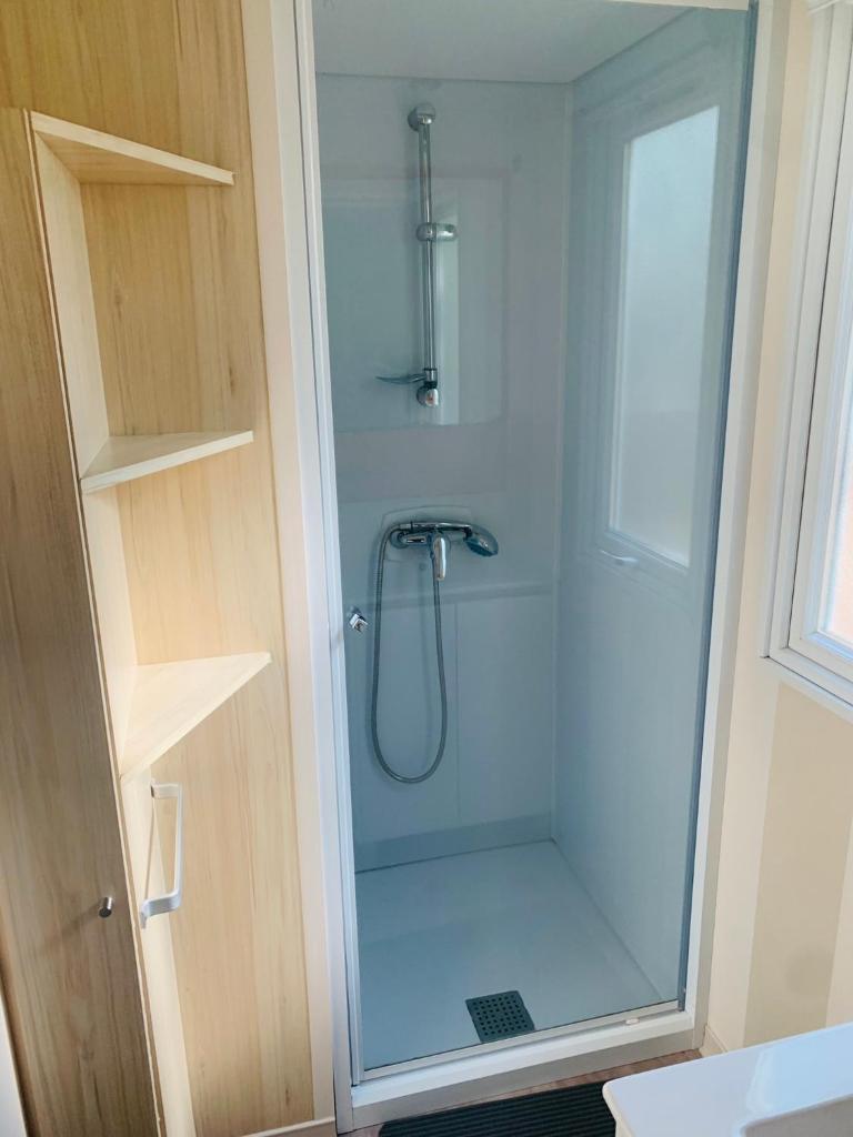 une douche avec une porte vitrée dans une salle de bain dans l'établissement Mobil-home, à Agde