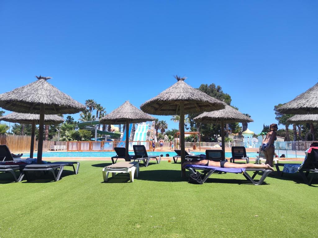 - un groupe de chaises longues et de parasols à côté de la piscine dans l'établissement LocaMobi, à Torreilles