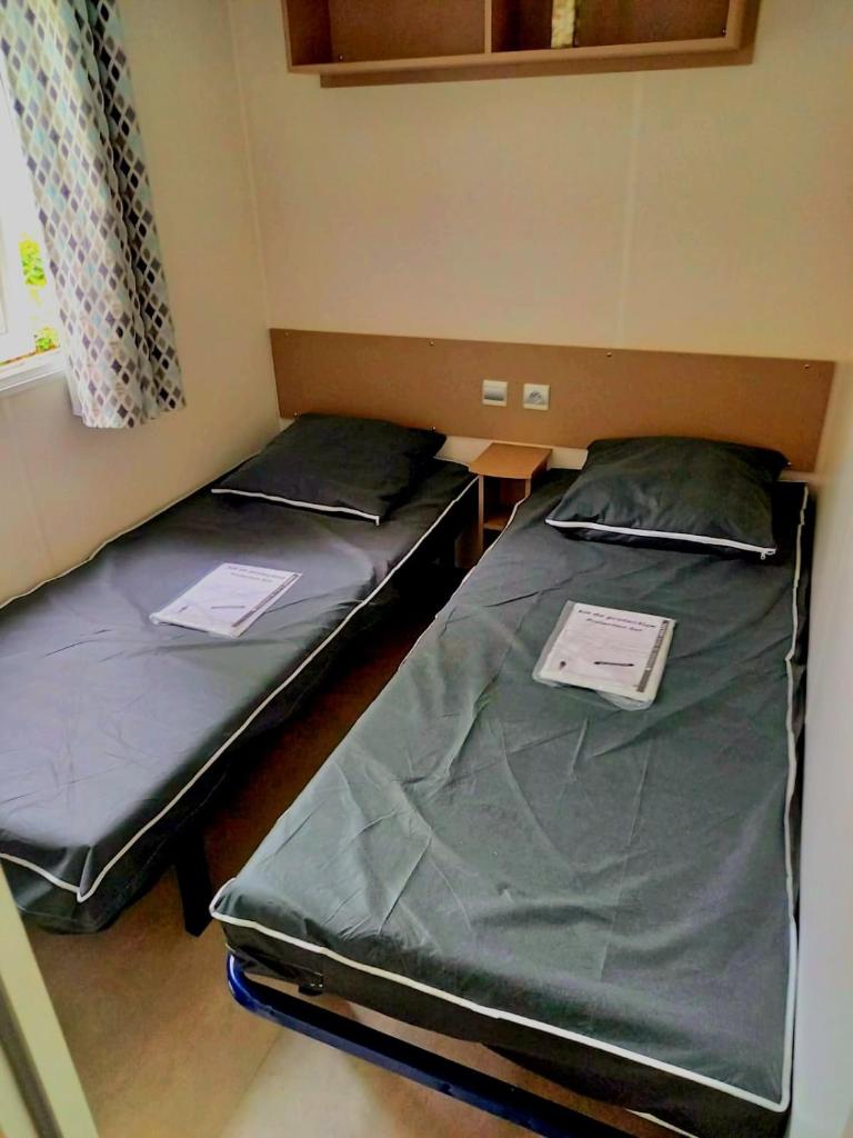 - 2 lits dans une petite pièce avec des papiers dans l'établissement Mobil Home Vias plage La Carabasse terrasse fermée hors saison, à Vias 37 autres photos