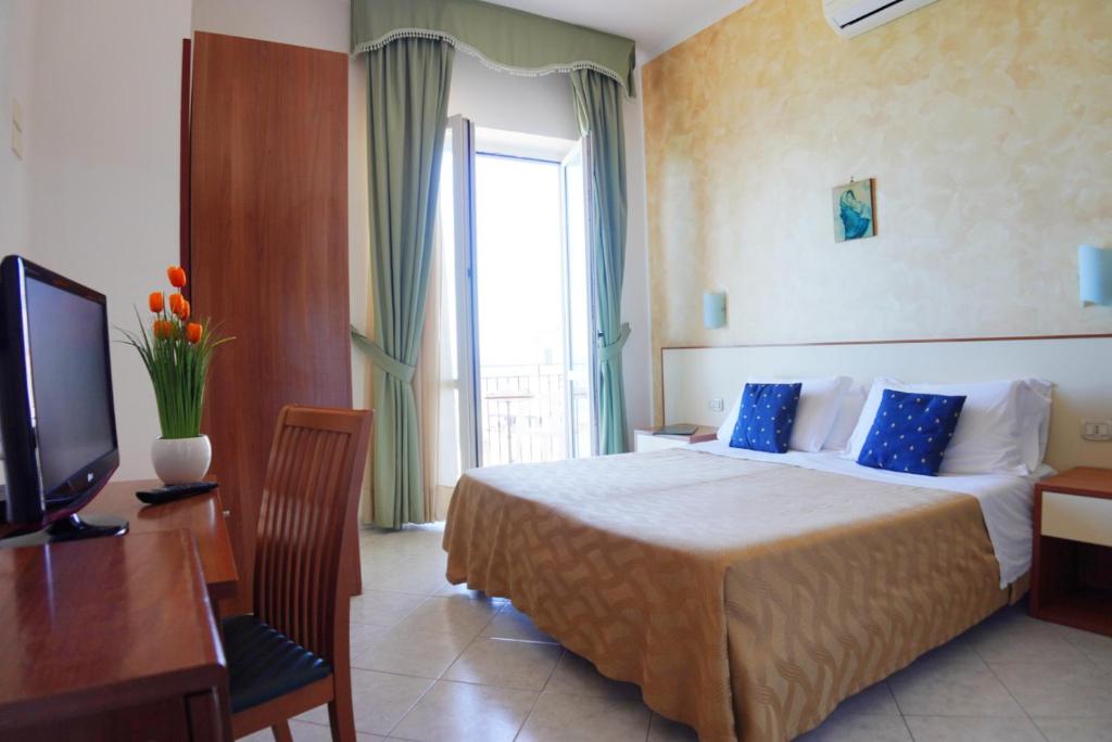 une chambre d'hôtel avec un lit, un bureau et une télévision dans l'établissement New Hotel Sonia, à Santa Maria di Castellabate