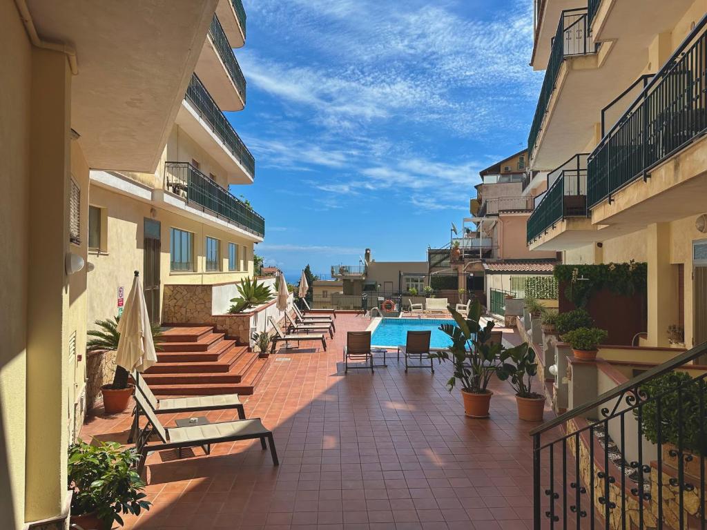 un balcon avec des bancs et une piscine dans un immeuble dans l'établissement Hotel Soleado, à Taormine