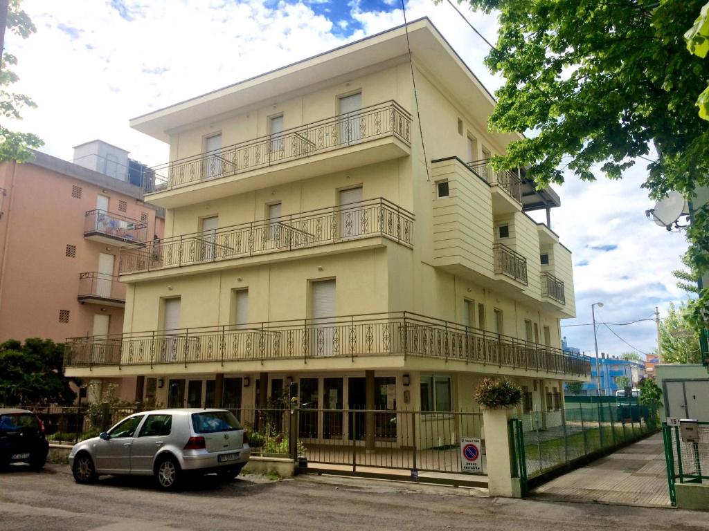 un grand bâtiment jaune avec des balcons dessus dans l'établissement Hotel Monica, à Rimini