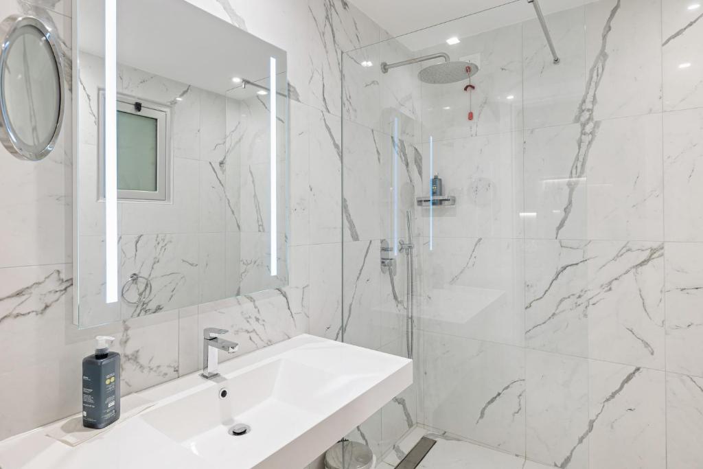 une salle de bain blanche avec un lavabo et un miroir dans l'établissement Aldiana Club Rocca Nettuno Calabria, à Tropea