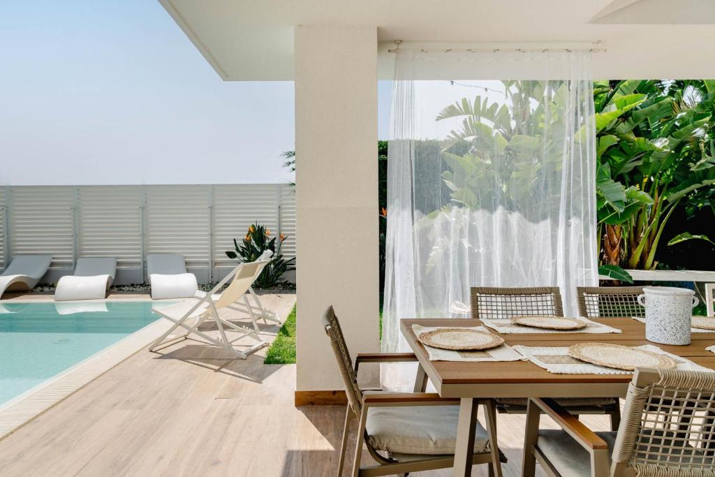 - une salle à manger avec une table et des chaises à côté de la piscine dans l'établissement Villa Luce Luxury Accomodation, à Polignano a Mare