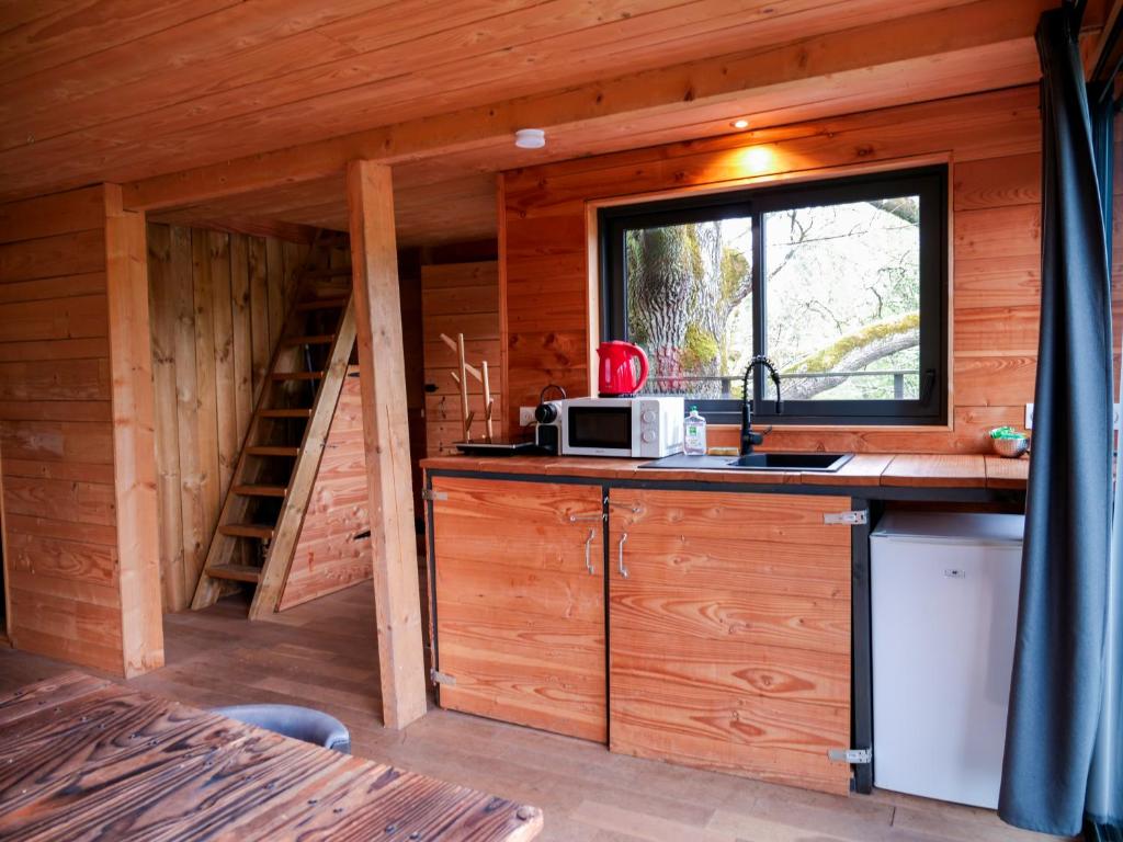 - une cuisine dans une cabane en rondins avec un évier et une fenêtre dans l'établissement Cabane perchée - lac privé, spa & nature, à Sadirac