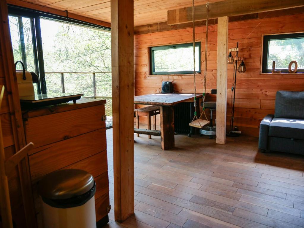une chambre avec une table et un canapé dans une cabine dans l'établissement Cabane perchée - lac privé, spa & nature, à Sadirac