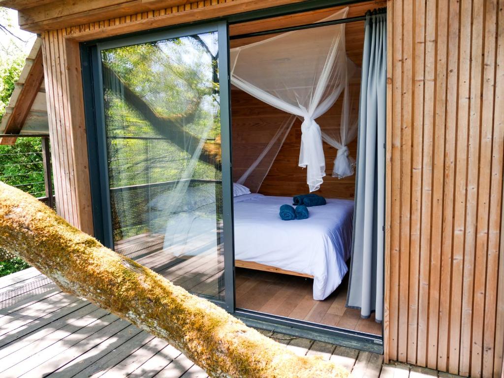 une chambre avec un lit et une fenêtre donnant sur une terrasse dans l'établissement Cabane perchée - lac privé, spa & nature, à Sadirac 14 autres photos