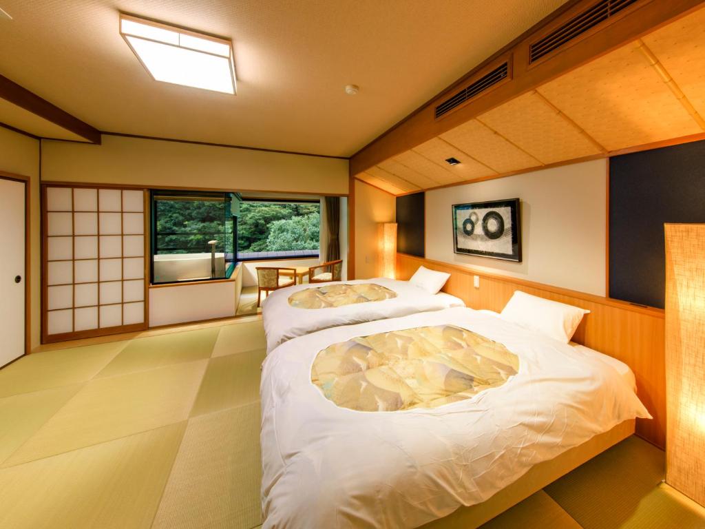 deux lits dans une chambre avec deux fenêtres dans l'établissement Hotel Okuyumoto, à Hakone 149 autres photos