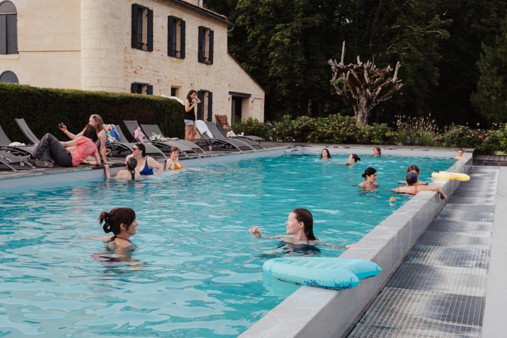 un groupe de personnes nageant dans une piscine dans l'établissement Cabane perchée - lac privé, spa & nature, à Sadirac