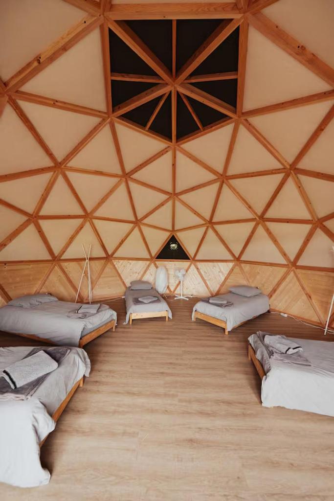 une chambre avec quatre lits dans une yourte dans l'établissement Évasion nature, dômes & lac privé près Bordeaux, à Sadirac 13 autres photos