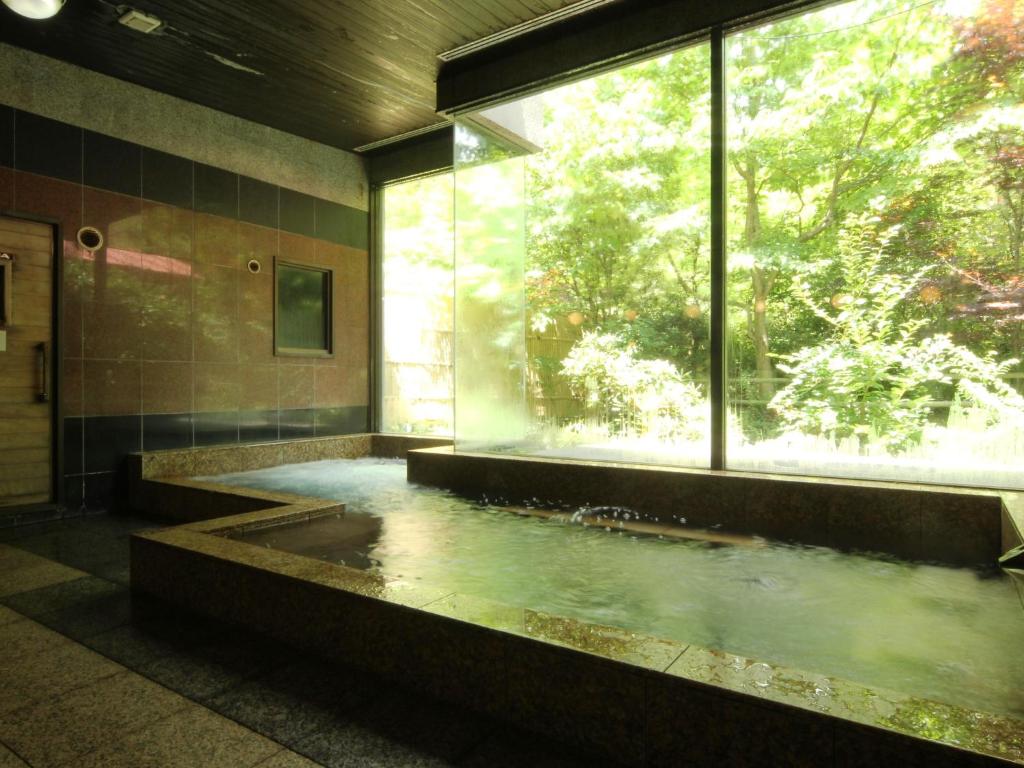 La salle de bains est pourvue d'une grande baignoire et d'une grande fenêtre. dans l'établissement Iwasu-so, à Nakatsugawa