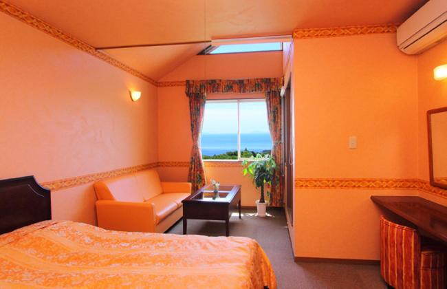 une chambre avec un lit, un canapé et une fenêtre dans l'établissement Nasubi no Hana, à Itō