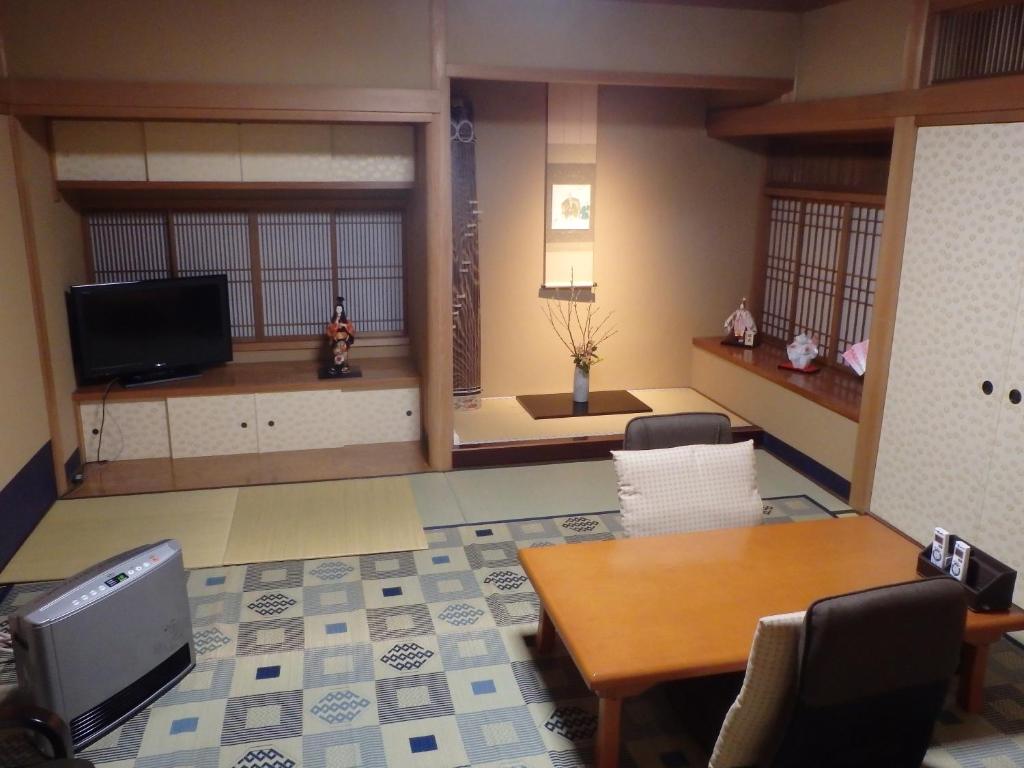 un salon avec une télévision, une table et des chaises dans l'établissement Kamuroan, à Kyoto
