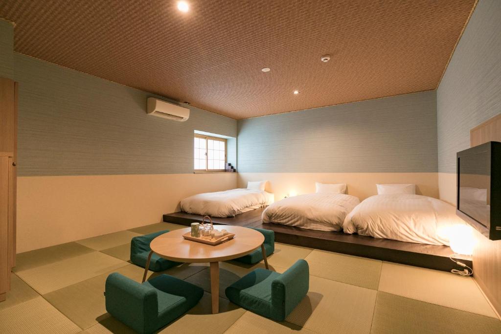 une chambre avec deux lits et une table et des chaises dans l'établissement Asobe, à Aso