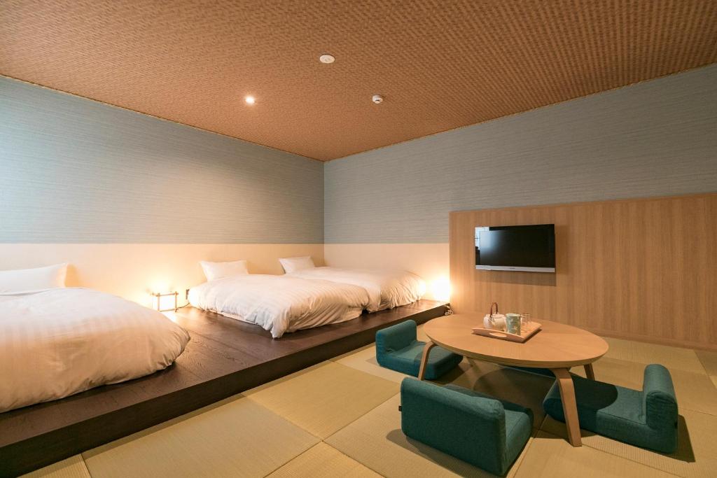 - une chambre avec 2 lits, une table et une télévision dans l'établissement Asobe, à Aso