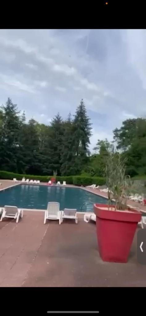 une piscine avec des chaises longues et une plante en pot dans l'établissement Mobil-home Saint-Chéron 91530 Camping Parc des roches, à Mirgaudon