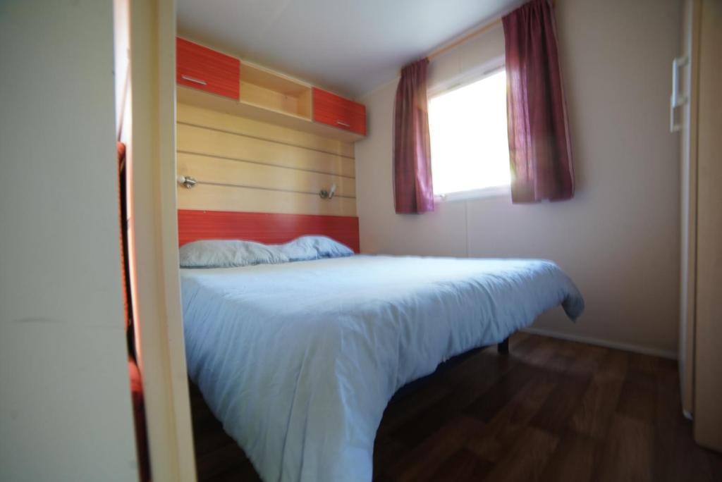 une chambre avec un lit blanc avec une fenêtre dans l'établissement Mobil-home Saint-Chéron 91530 Camping Parc des roches, à Mirgaudon 7 autres photos