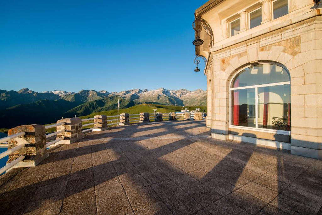 un bâtiment avec une clôture et des montagnes en arrière-plan dans l'établissement Villages Clubs du Soleil - SUPERBAGNERES, à Superbagnères