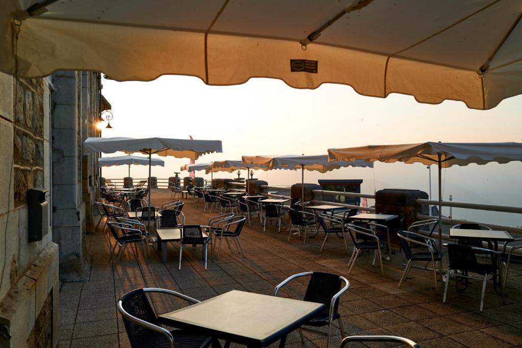 un restaurant en plein air avec tables, chaises et parasols dans l'établissement Villages Clubs du Soleil - SUPERBAGNERES, à Superbagnères