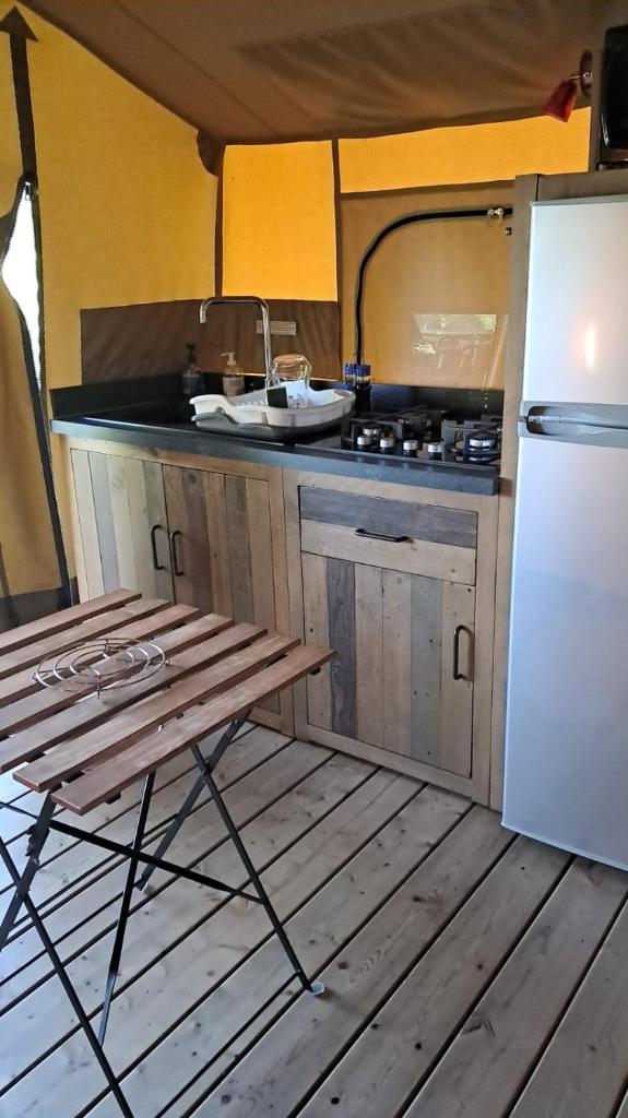 une cuisine avec une table et un réfrigérateur blanc dans l'établissement O'PHIL DE LAU, à Manciet