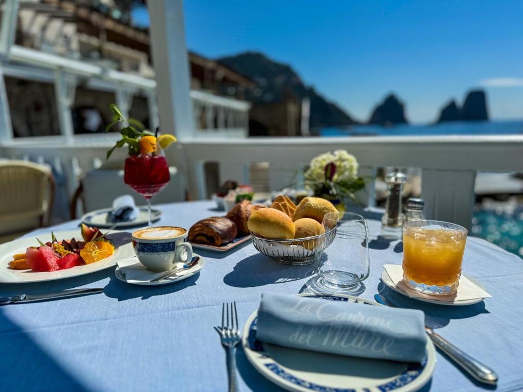 une table avec des assiettes de nourriture et de boissons dessus dans l'établissement Diva La Canzone Del Mare, à Capri