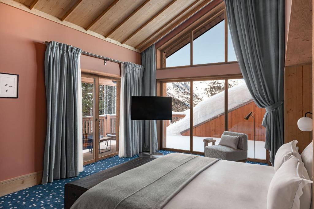 une chambre avec un lit et une grande fenêtre dans l'établissement Hotel Le Coucou Méribel, à Méribel