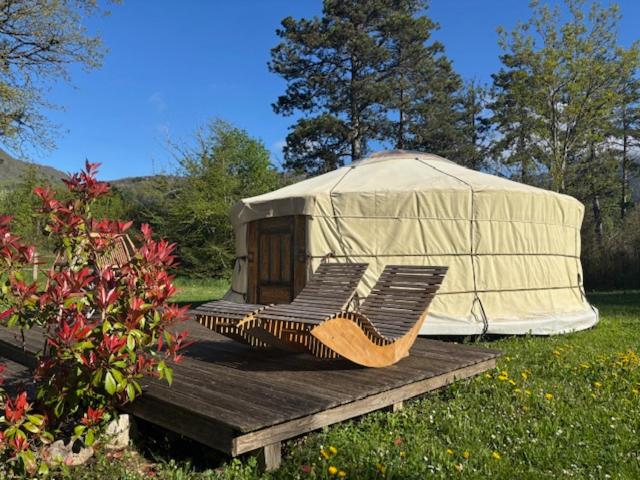 une yourte assise sur une terrasse en bois dans un champ dans l'établissement Yourte mongole, à Champfromier