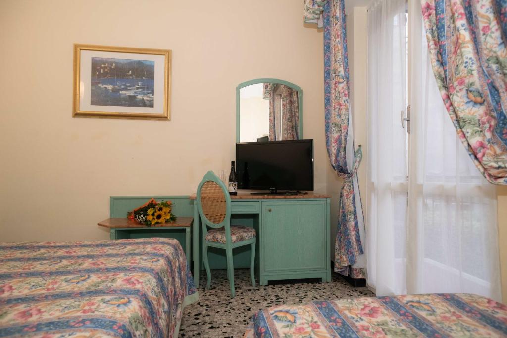 une chambre d'hôtel avec un lit et un bureau avec une télévision dans l'établissement Hotel Magnolia, à Albenga 36 autres photos