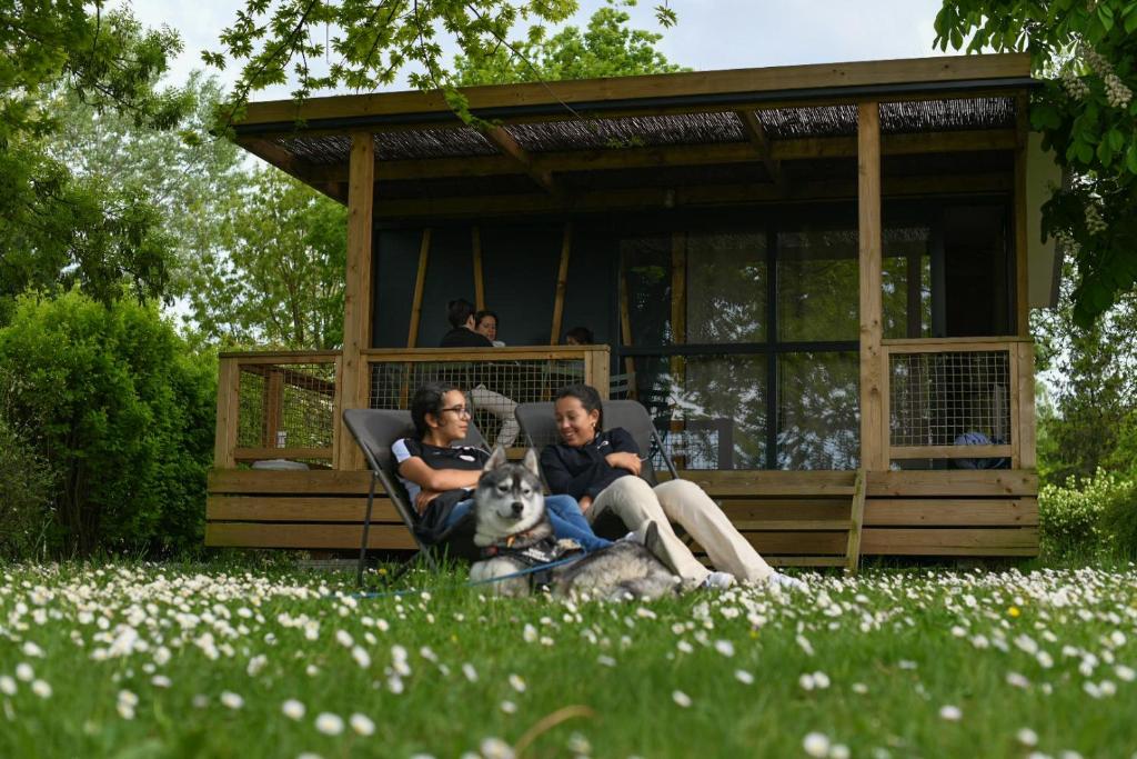un groupe de personnes assises dans un kiosque avec un chien dans l'établissement Camping Onlycamp le Champ d'été, à Reyssouze