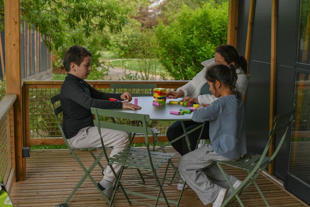 un groupe de personnes assises à une table sur une terrasse couverte dans l'établissement Camping Onlycamp le Champ d'été, à Reyssouze