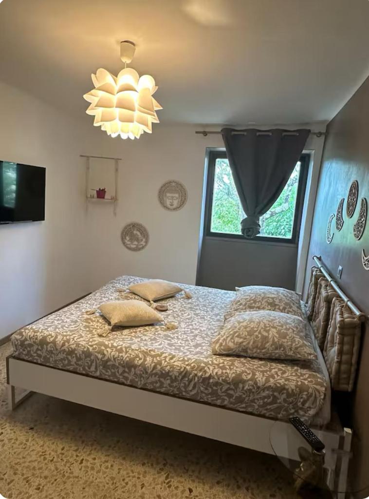 une chambre avec un lit, une fenêtre et un lustre dans l'établissement Gîte des Bourboul, à Grospierres