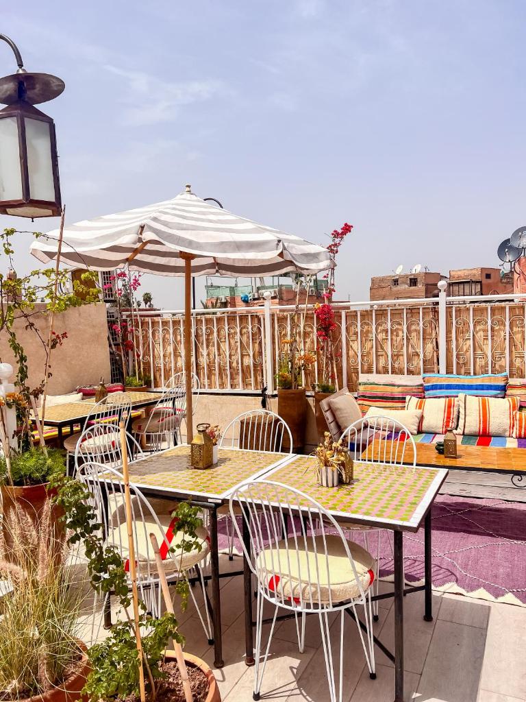 un patio avec tables, chaises et un parasol dans l'établissement Riad 10 Mandarin BOUTIQUE RIAD, à Marrakech