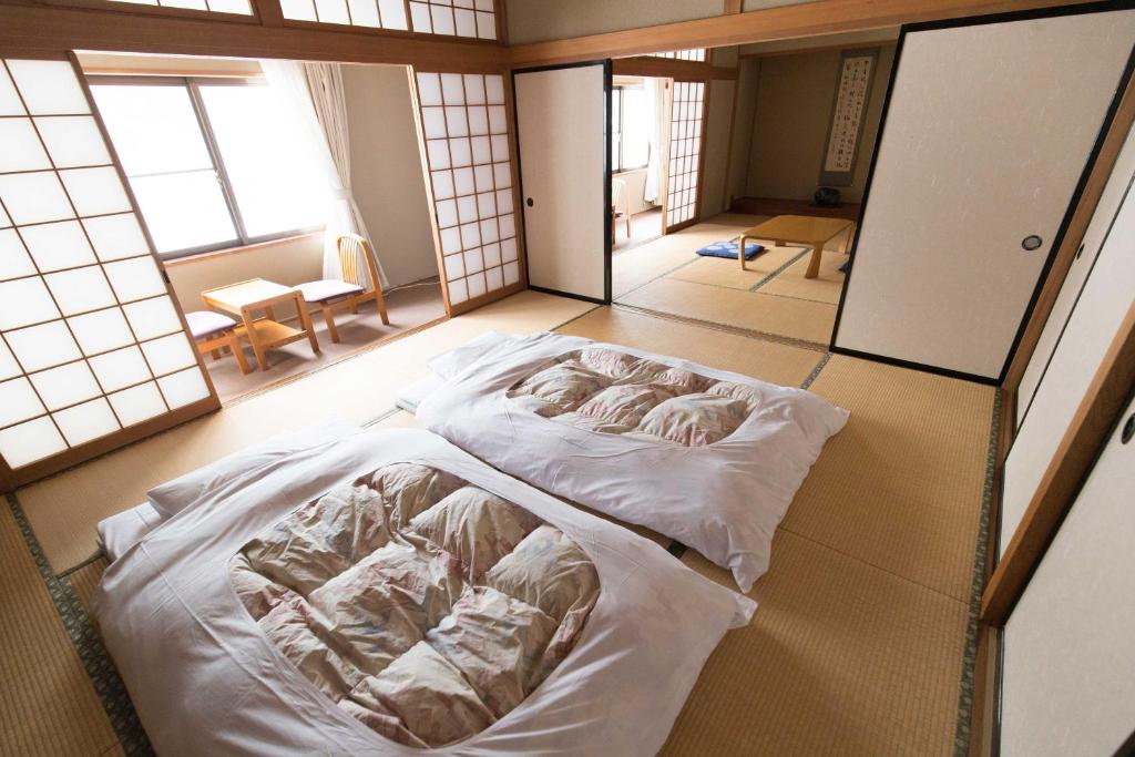 Cette chambre comprend un grand lit et des fenêtres. dans l'établissement Sagirisou, à Nagano