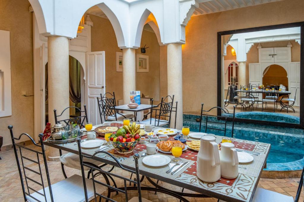 une salle à manger avec une table et une piscine dans l'établissement RIAD AWINATI Location Privatisée ,piscine chauffée , beau Rooftop, à Marrakech