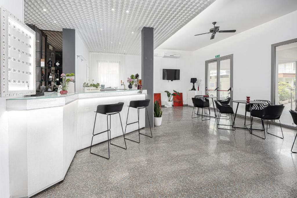 une cuisine blanche avec des chaises noires et un bar dans l'établissement BI Hotel, à Bellaria-Igea Marina