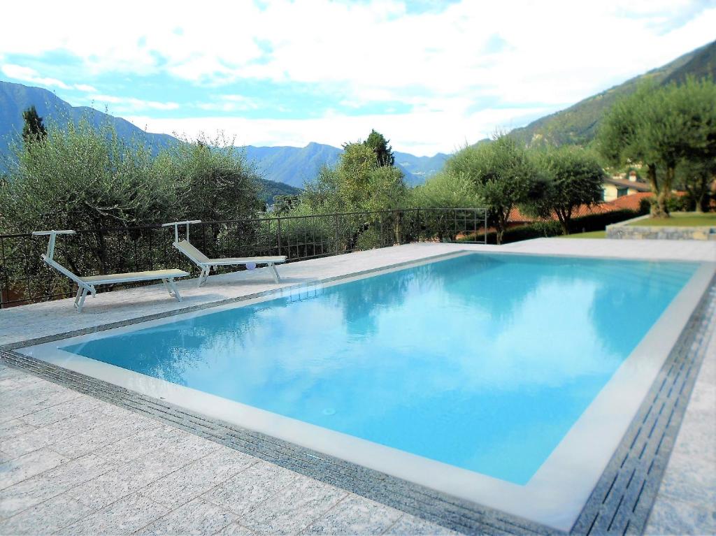 une piscine avec deux bancs à côté dans l'établissement Villa Oliva, à Tremezzo