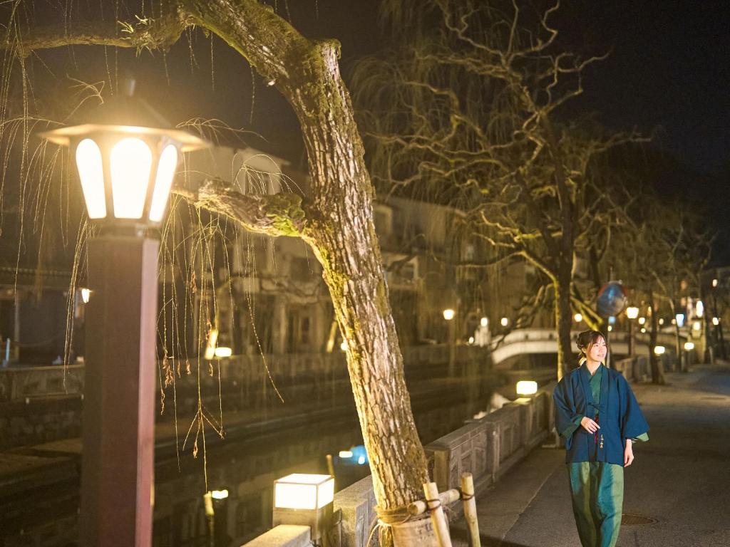 un homme marchant sur un trottoir à côté d'un lampadaire dans l'établissement Sinonomesou Kinosaki Onsen, à Toyooka