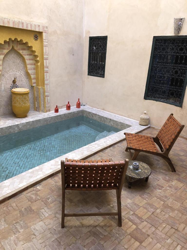 - une piscine avec 2 chaises, une table et un banc dans l'établissement Riad Paquerette, à Marrakech
