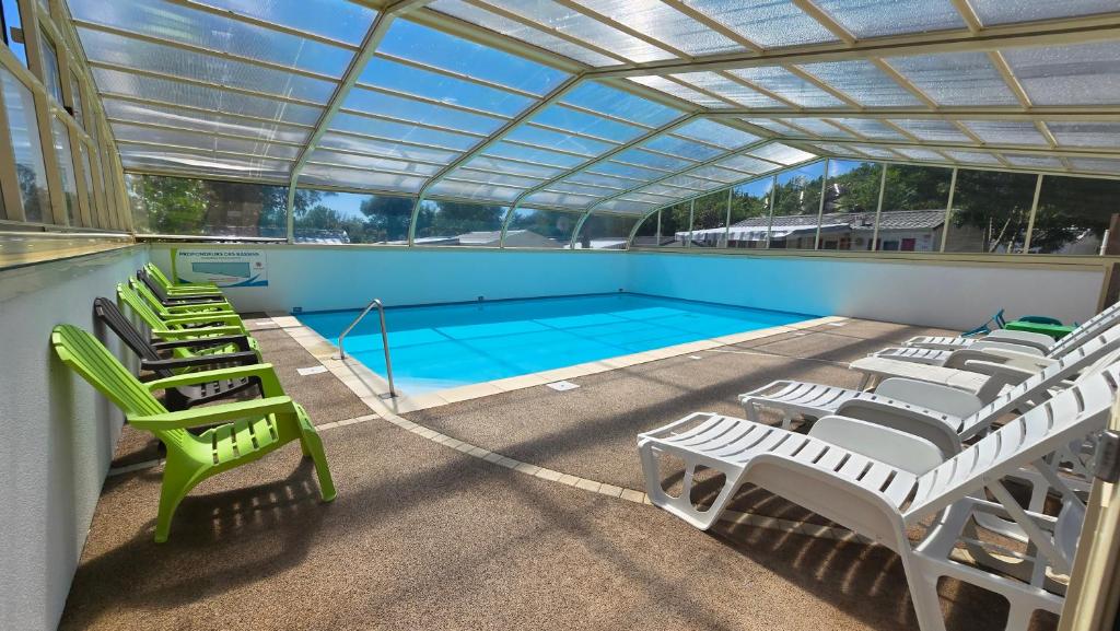 une piscine avec des chaises longues vertes et une piscine dans l'établissement Camping les Mancellieres, à Avrillé