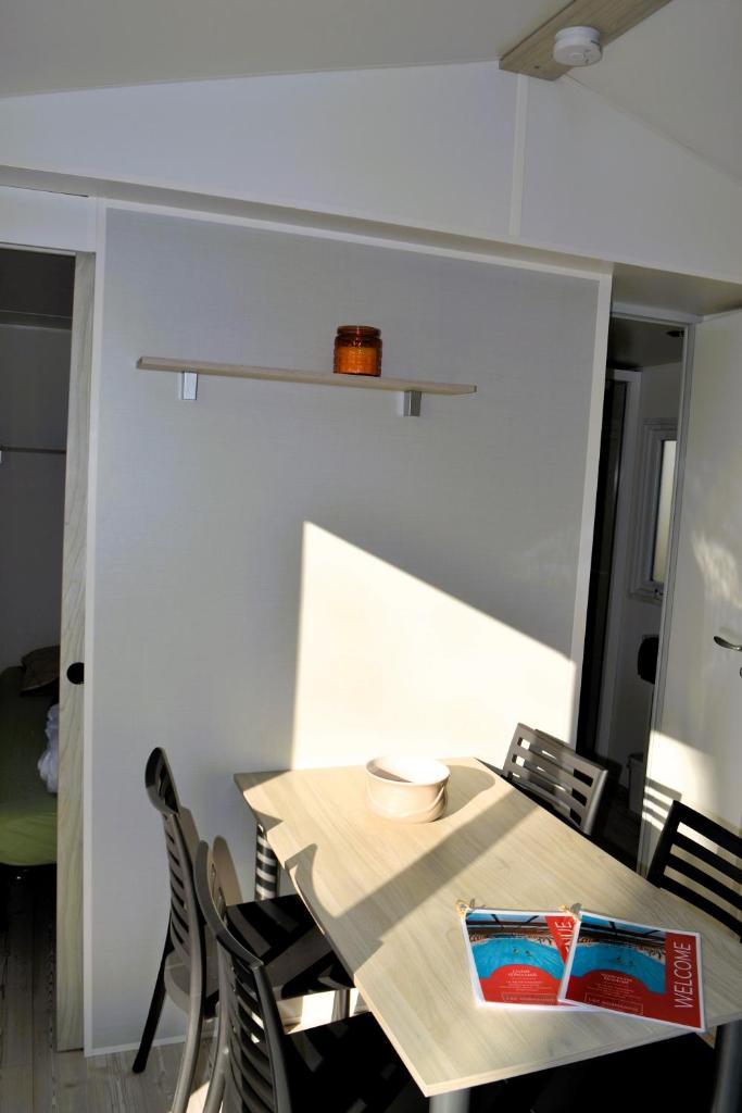une table et des chaises dans une pièce avec un mur blanc dans l'établissement Le Petit Paradis, à Litteau