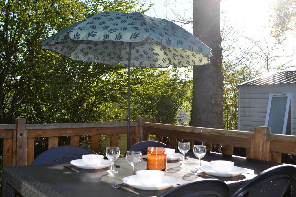 une table avec un parapluie, des assiettes et des verres dans l'établissement Le Petit Paradis, à Litteau