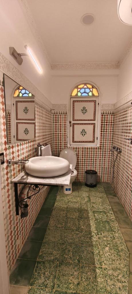 La salle de bains est pourvue d'une baignoire, d'un lavabo et de 2 fenêtres. dans l'établissement Riad golf stinia, à Meknès