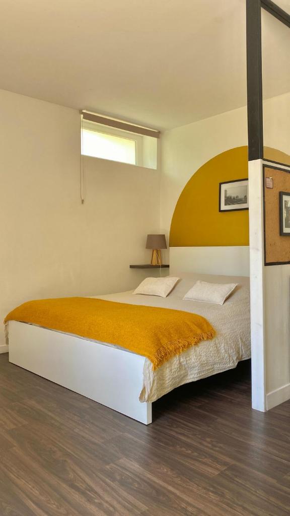 une chambre avec un grand lit avec une couverture orange dans l'établissement Agréable petit gîte avec jardinet et piscine, à Salies-de-Béarn